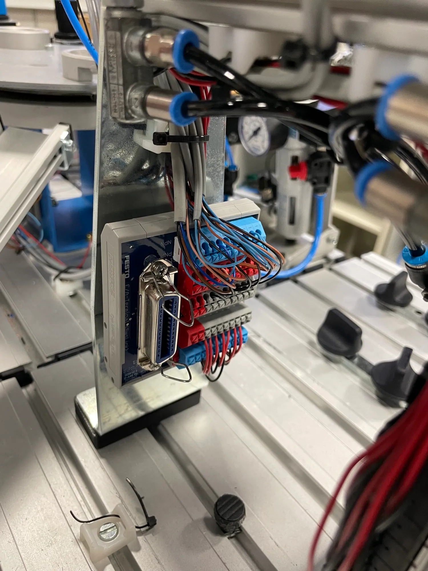 Close-up of the Festo I/O terminal with its connector and color-coded wires from the station's sensors and valves.